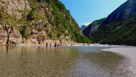 Jóvenes-Disfrutando-Del-Valle-Paradisíaco-Con-Agua-Cristalina-Del-Río-Flotando-A-Través-De-Montañas-Rocosas-En-Los-Alpes-Albaneses