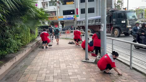 Scene-of-a-group-of-cleaners-sweeping-the-floor,-clearing-litter,-and-picking-up-debris-and-leaves-on-the-pavement-in-Johor-Bahru,-Malaysia