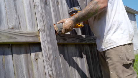 White-man-uses-power-tool-to-cut-away-fence-on-hot-summer-day