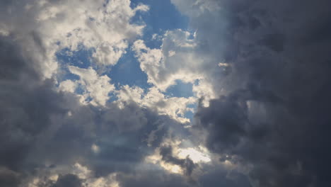 Fixed,-static-shot-of-blue-sky-filled-with-white-clouds-with-sunlight-divinely-piercing-through-them