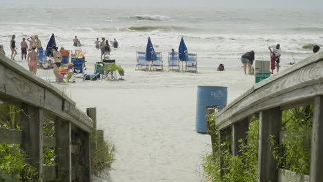 Groups-of-People-at-the-Beach-Through-Guardrails-Mid-Day,-Static