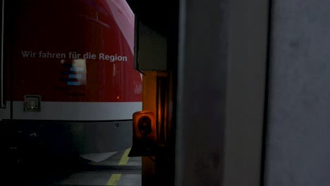 Primer-Plano-De-Un-Moderno-Tren-Regional-Rojo-Con-La-Marca-Stuttgart,-Parado-En-Las-Vías-Al-Atardecer