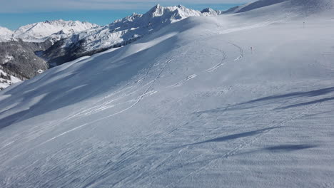 Panoramic-view-of-a-pristine-ski-slope-and-the-Montafon-range-valley-of-the-Austrian-Alps,-slow-motion