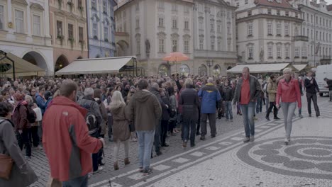 Crowded-scene-in-Prague's-historic-square-with-a-mix-of-tourists-and-locals-during-the-day,-tilt-down-shot