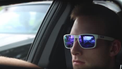 Un-Hombre-Guapo-Con-Gafas-De-Sol-Conduciendo-Por-El-Espejo-Retrovisor