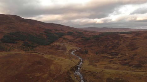 Aerial-shot-of-a-river-in-the-Scottish-Highlands-in-beautiful-autumn-colors