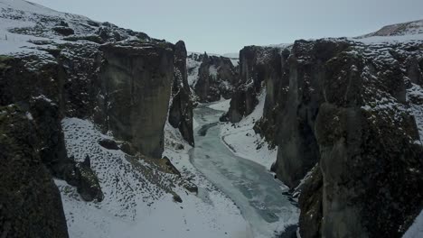 Iceland-Gorge-with-Ice-and-Snow-Covering-the-Landscape-with-an-Aerial-Drone-Reversing