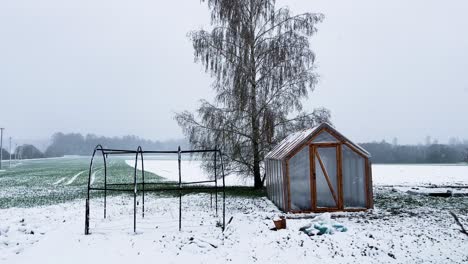 Invernadero-En-El-Jardín-Durante-Una-Repentina-Tormenta-De-Nieve-En-Abril,-Letonia