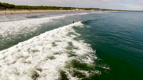 Drone-shot-following-a-surfer-riding-a-wave-from-behind-on-a-summer-day