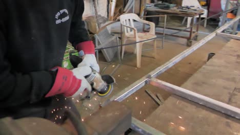 worker-uses-a-portable-metal-grinder-to-smooth-out-aberrations-in-a-welded-aluminum-frame
