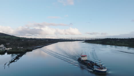 Erskine,-Scotland-beautiful-sunset-over-river-tracking-with-a-working-boat-as-we-pass-it-through-frame