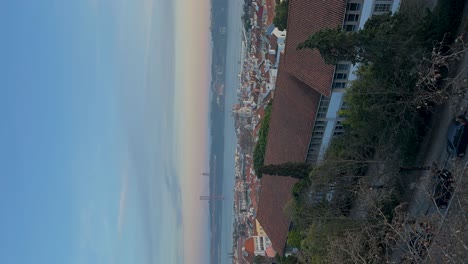 Vertical-video-captures-the-Lisbon-area-with-a-bridge-spanning-across-the-river-on-the-horizon,-illustrating-the-concept-of-urban-exploration-and-architectural-marvels