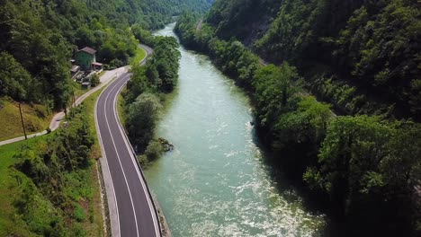 Drone-shot-of-the-Sava-River,-Trbovlje,-Slovenia,-flowing-surrounded-by-a-green-forest