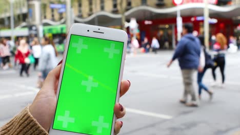 Holding-a-green-screen-phone-in-a-busy-street