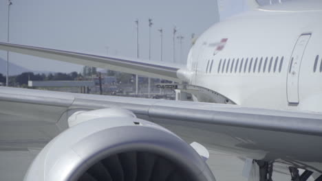 Close-Up-of-Airplane-Exhaust-and-Jet-Turbine-Spinning-While-Plane-is-Parked-at-Terminal