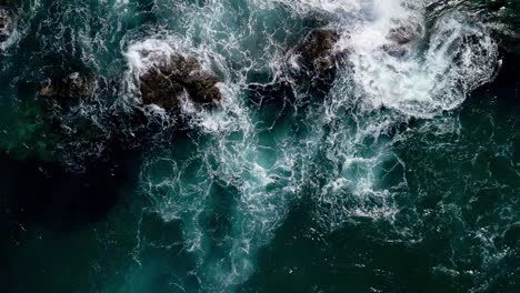 Aerial-View-Over-Ocean-Waves-Crashing-Over-Rocks-in-Slow-Motion,-Top-Down-View-in-Slow-Motion