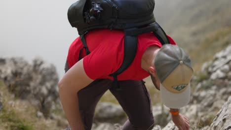 Un-Excursionista-Caucásico-Con-Camisa-Roja-Y-Mochila-Sube-Por-Una-Empinada-Pendiente-Rocosa