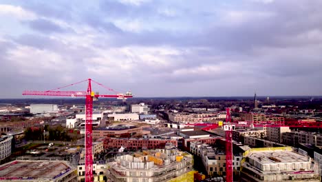 Aerial-descending-movement-showing-red-cranes-rising-above-residential-area