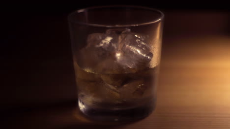 Glass-of-Whiskey,-Bourbon-or-Rum-on-the-rocks,-watch-the-ice-melting-with-this-time-lapse-footage