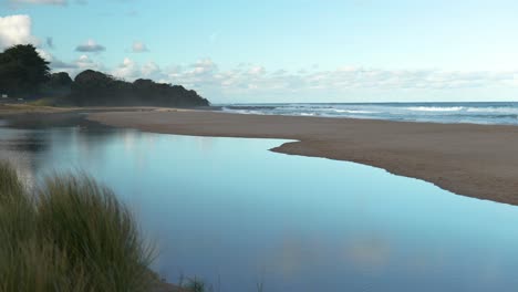 Ruhige-Strandszene-Mit-Atemberaubenden-Reflexionen-Schimmern-Aus-Ruhigem-Wasser