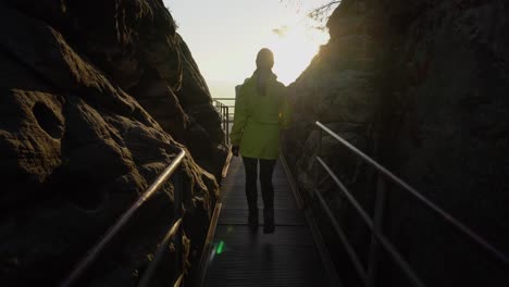 Outdoor-Mädchen-In-Gelber-Jacke-Läuft-Auf-Brücke-Gegen-Die-Sonne,-Gimbal-Aufnahme