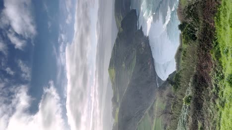 Vertical-video-of-the-rhythmic-ocean-waves-cascading-onto-the-shores-of-the-Portuguese-Riviera-in-Açores,-Portugal,-encapsulating-the-serene-coastal-charm-and-breathtaking-natural-scenery