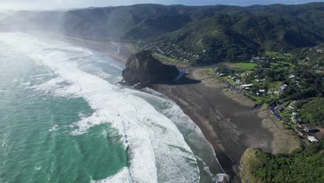 Schaumige-Wellen-Plätschern-An-Der-Sandküste-Von-Piha-Beach,-Nordinsel,-Neuseeland---Luftaufnahme-Einer-Drohne