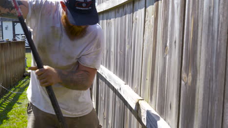 Determined-man-uses-prybar-during-fence-repair