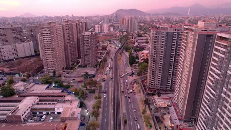 Vicuña-mackenna-avenue-with-subway-line-5-tracks-above-the-road-at-dusk,-santiago,-aerial-view