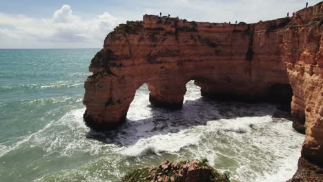 Zwei-Natürliche-Bögen-Mit-Felsnadeln-Und-Wellen,-Die-Auf-Die-Malerischen-Klippen-Der-Estrada-Da-Caramujeira-Krachen.-4K-Luftaufnahme-Einer-Drohne-In-Der-Algarve-In-Portugal