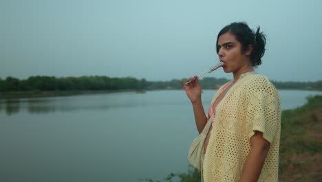 Woman-in-thought-by-a-tranquil-river-at-dusk,-natural-light,-serene-scene,-side-view