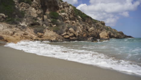 Waves-splashing-on-seashore-by-rock-in-slow-motion