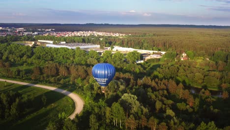 Areal-view-of-hot-air-ballon-flying-over-small-forest-and-near-river