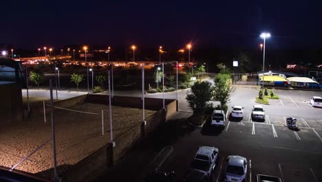 Carpark-next-to-volleyball-court-with-timelapse-motion-of-cars-at-night