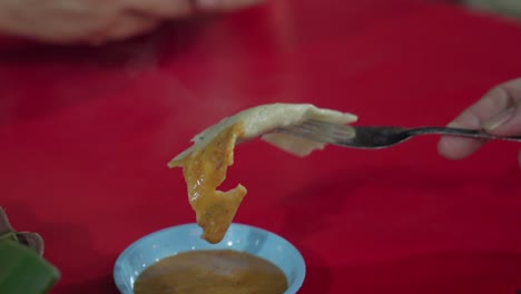 Dipping-Otak-Otak-Asian-Fish-Cake-In-Sauce-Using-Fork-in-Restaurant,-Close-Up
