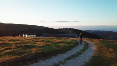 Mountain-biker-driving-up-the-hill-on-macadam-road-during-sunset