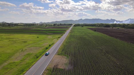 Una-Toma-Aérea-De-Un-Vehículo-Toyota-Chr-Azul-Conduciendo-Por-Una-Carretera-Recta-En-El-Campo-De-Lopburi,-Tailandia