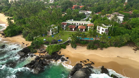 Vista-Aérea-Que-Se-Aleja-De-Un-Resort-Y-Sobre-Una-Playa-Rocosa-En-Sri-Lanka