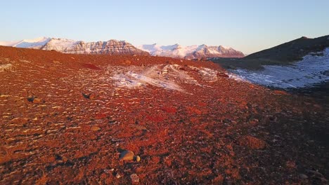 Secuencia-Cinematográfica-De-Apertura-En-Islandia-Sobre-Rocas-Cálidamente-Iluminadas-Por-La-Luz-Del-Sol-Para-Revelar-Icebergs-Glaciares-Flotando-En-El-Lago,-Fondo-Montañoso