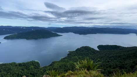 Ultrawide-high-angle-pan-of-mountains-and-forest-surrounding-Lake-Waikaremoana,-New-Zealand