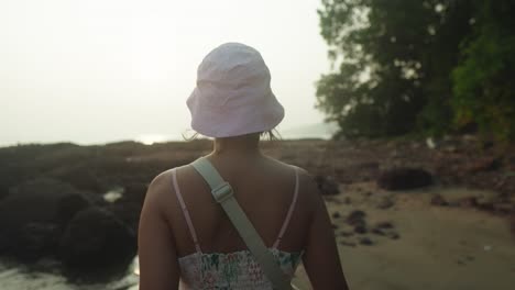 Junge-Frau-Mit-Hut,-Von-Hinten-Gesehen,-Mit-Blick-Auf-Den-Strand-Bei-Sonnenuntergang