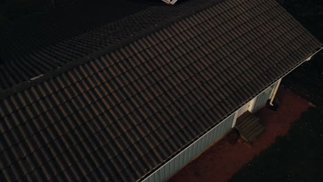 Drone-inspection-of-the-condition-of-a-tiled-house-roof,-on-a-fall-evening