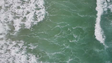 Top-Down-View-Over-Ocean-Waves-Along-the-Cornish-Coastline-in-Slow-Motion