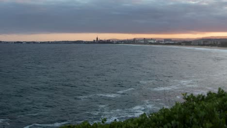 Windiges-Meer-Bei-Sonnenuntergang-Mit-Entfernter-Industrielandschaft-In-Wollongong,-NSW