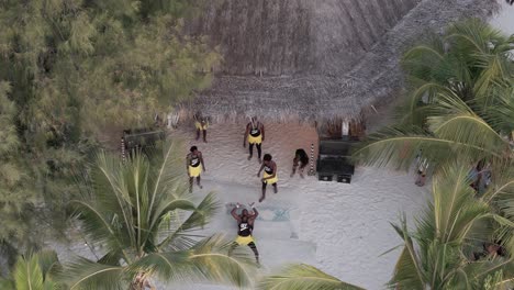Aerial-view-overlooking-colourful-group-of-athletic-dancers-performance-on-Michamvi-Kae-beach-in-Zanzibar