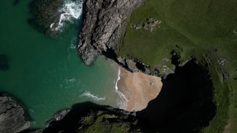 Strandbucht-In-Cornwall,-Abgeschieden-Von-Felsigen-Klippen,-Aus-Einer-Luftdrohne-Von-Oben-Nach-Unten,-Die-Sich-Beim-Abstieg-Dreht
