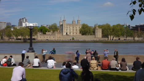 Time-lapse-of-tourists-on-the-bank-of-the-river-Thames,-London-with-the-Tower-of-London-on-the-far-bank