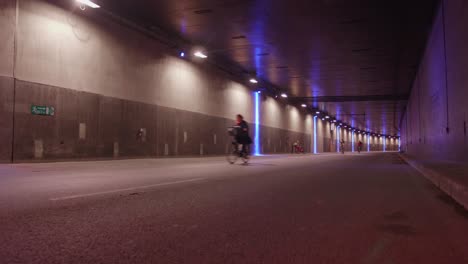 Cyclists-Biking-On-Car-free-Illuminated-Underground-Tunnel