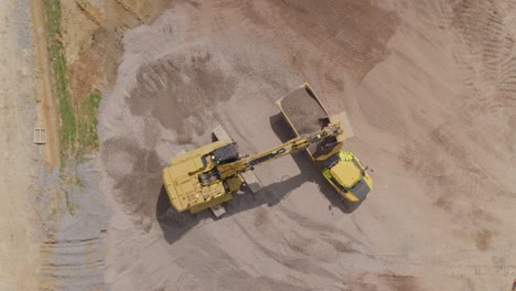 An-excavator-uploads-gravel-into-a-dump-truck-on-a-large-construction-site