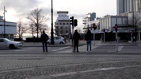 Menschen,-Die-Herumlaufen-Und-Darauf-Warten,-über-Die-Straße-Zu-Kommen,-Während-Der-Verkehr-Stark-Ist-Und-Der-Abend-Hereinbricht